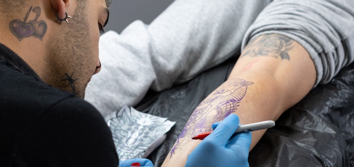 Tatuador hace marcas en la pierna del cliente