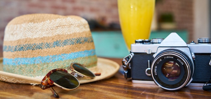 Gafas, sombreo y cámara fotográfica como símbolo del verano.