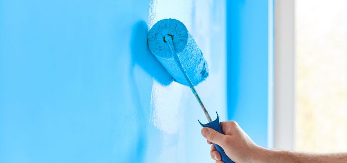 Persona pintando una pared con un rodillo 