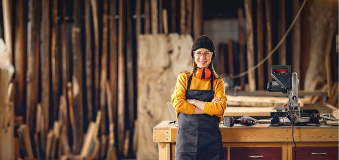 Mujer en un taller de carpintería pensando en ideas de negocio con madera