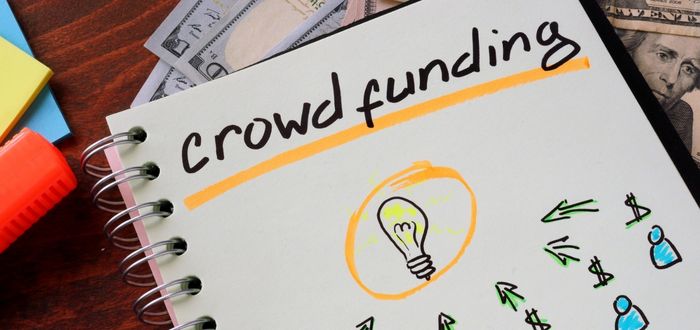 Libreta con la palabra crowdfundig y dibujos de bombillos como signo de ideas
