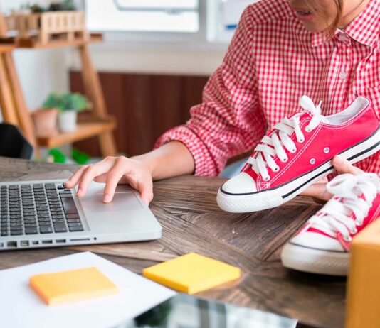 Productos para revender rentables | Todo lo que debes saber para hacerlo con éxito persona sosteniendo tennis sobre una mesa mientras opera un computador