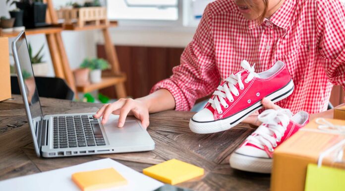 Productos para revender rentables | Todo lo que debes saber para hacerlo con éxito persona sosteniendo tennis sobre una mesa mientras opera un computador