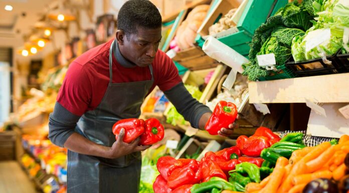 Cómo montar una tienda de barrio | Paso a paso y 7 ideas de qué locales poner hombre en tienda de barrio acomodando unos pimentones