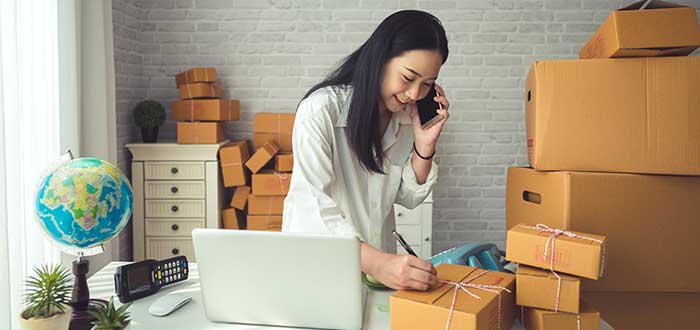 mujer marcando cajas para enviar por negocio por internet