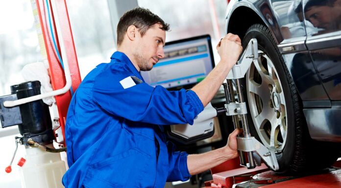 Cómo montar un taller de alineación y balanceo de automóviles Hombre haciendo mantenimiento a un neumático en un taller de mecánica