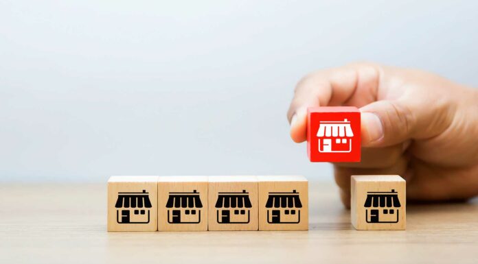 Franquicias «Low Cost» | Las mejores y más baratas opciones en el mercado para invertir Cajitas pequeñas con íconos de franquicias alineadas. Una mano levanta una de ellas.