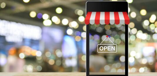 5 ventajas de los negocios online frente a los modelos tradicionales Teléfono móvil sobre una mesa con la imagen de un negocio